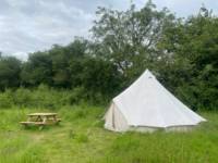 5m Bell tent with outdoor bed under a tree