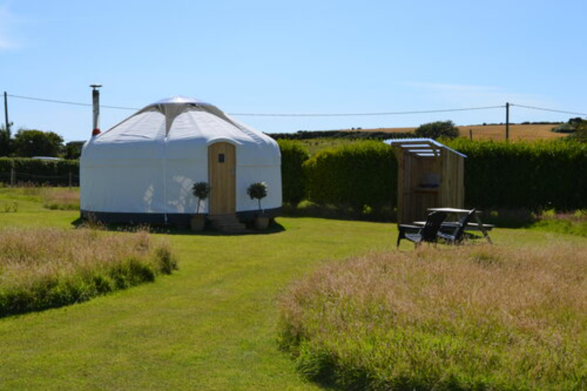 Outside, each yurt has a kitchen hut and a picnic table.